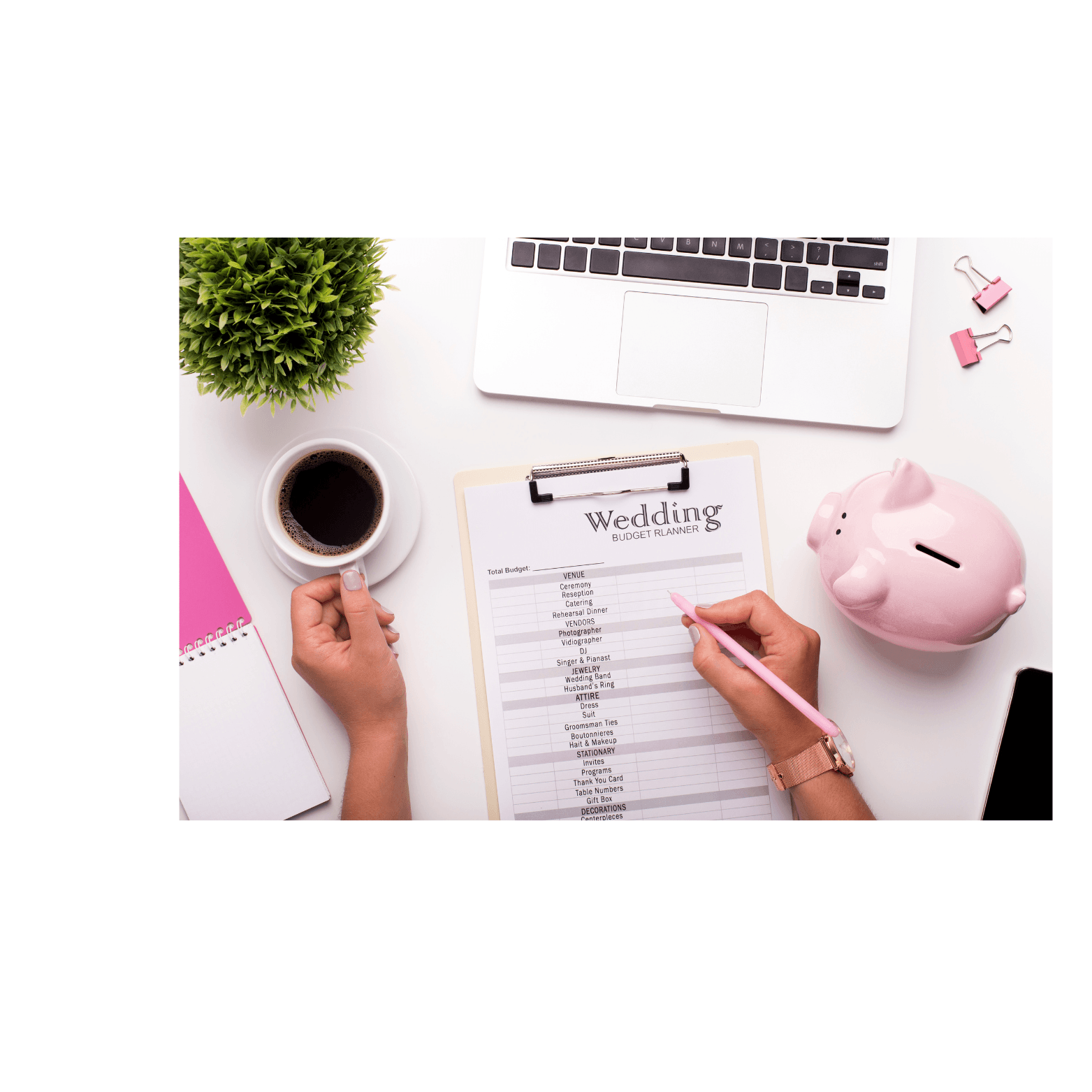 A wedding budget planner clipboard, piggy bank, coffee and planning notes on a white desk